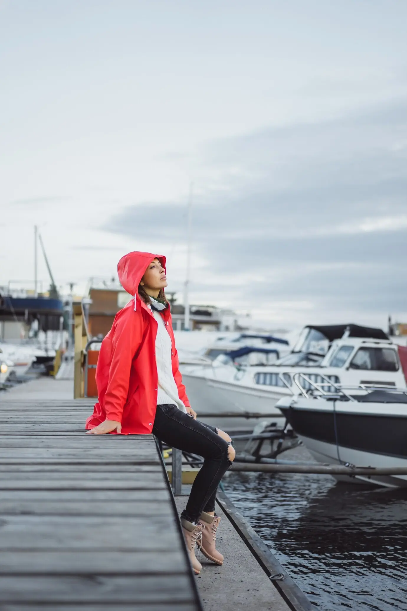 A beautiful young woman wearing a red cloak in the yacht port of Stockholm, Sweden.