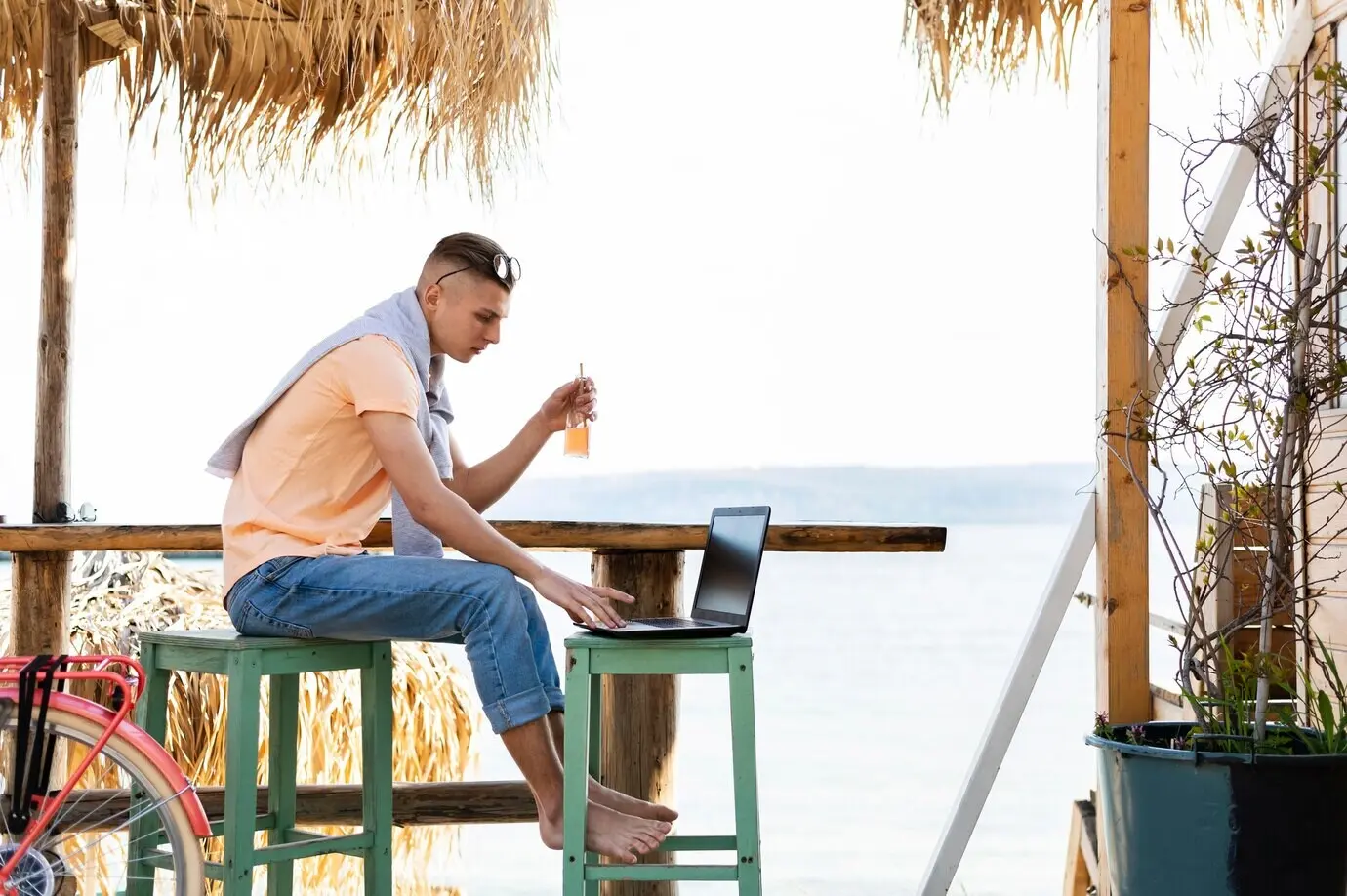Full-body shot of a man working on a laptop outdoors.